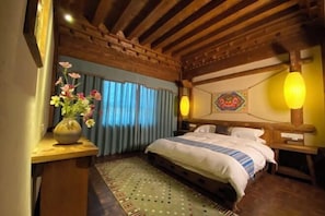 A bedroom with a wooden ceiling, a bed with white bedding, a vase with flowers on a wooden nightstand, and a patterned rug. - Shangri-La Fanyue Mountain Resort (Shangri-La)