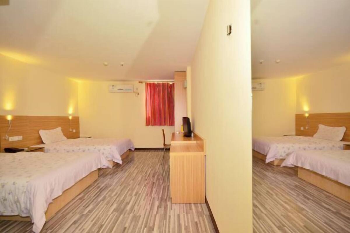 A hotel room with two beds, a wooden desk, and a red curtain.