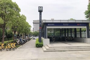 A modern bus station with a covered waiting area, a clear signboard, and a bike parking area.