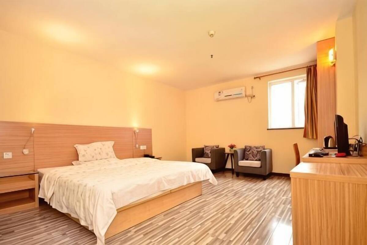 A hotel room with a bed, a desk, a chair, and a window.