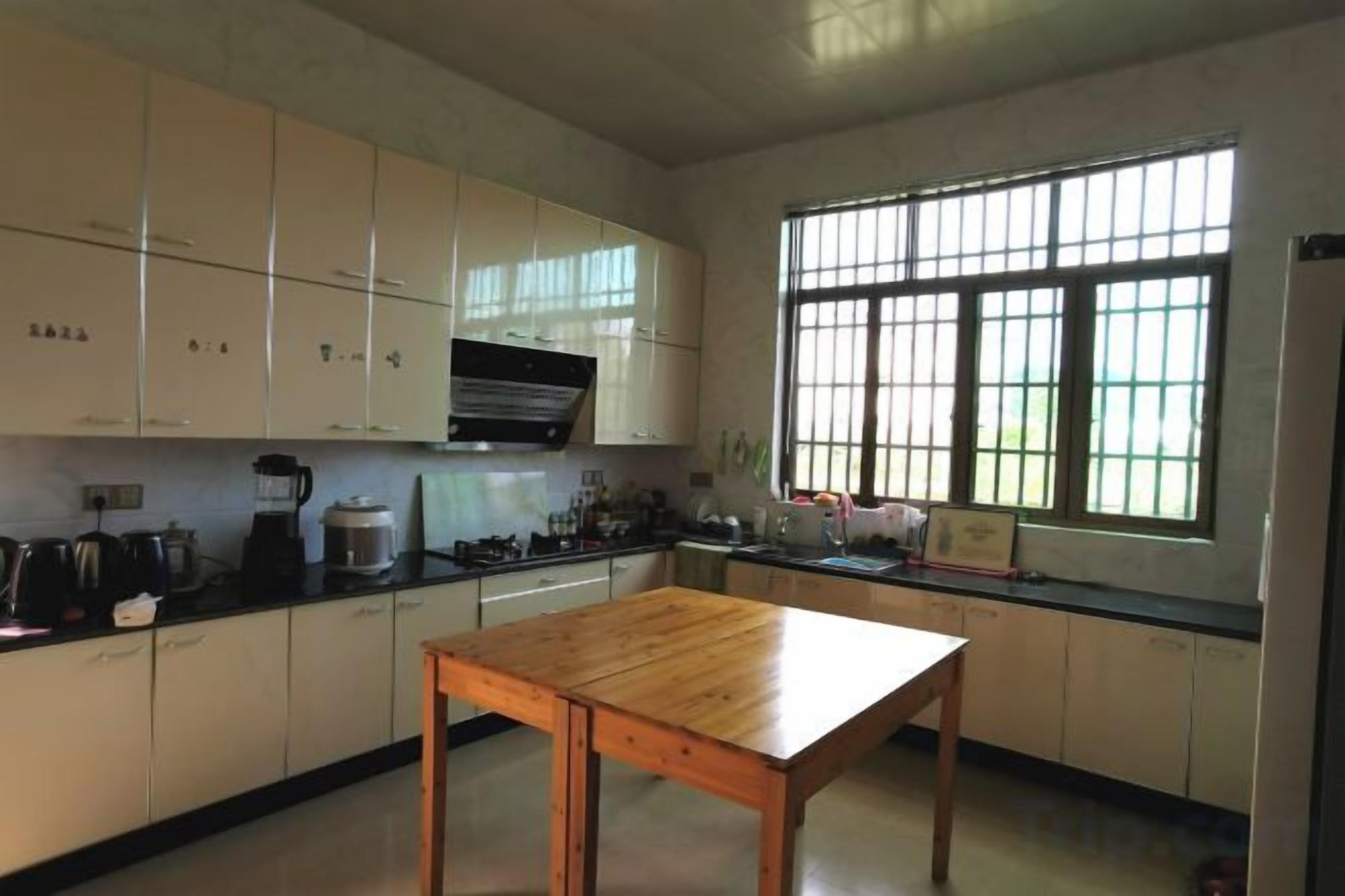 A kitchen with white cabinets, a wooden table, and a window providing natural light.