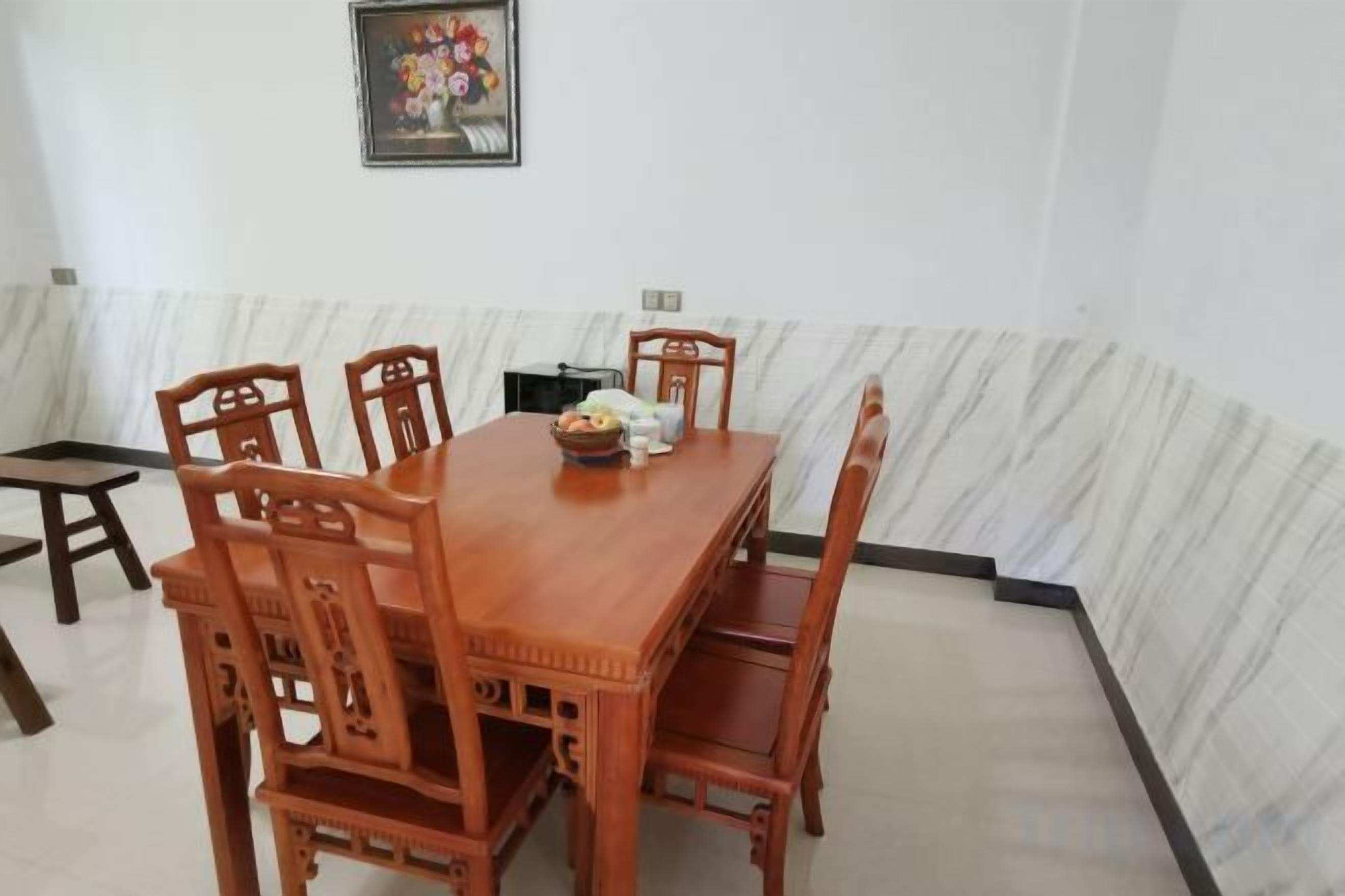 A dining area with a wooden table and chairs, a small side table, and a framed picture on the wall.