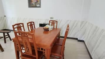 A dining area with a wooden table and chairs, a small side table, and a framed picture on the wall.