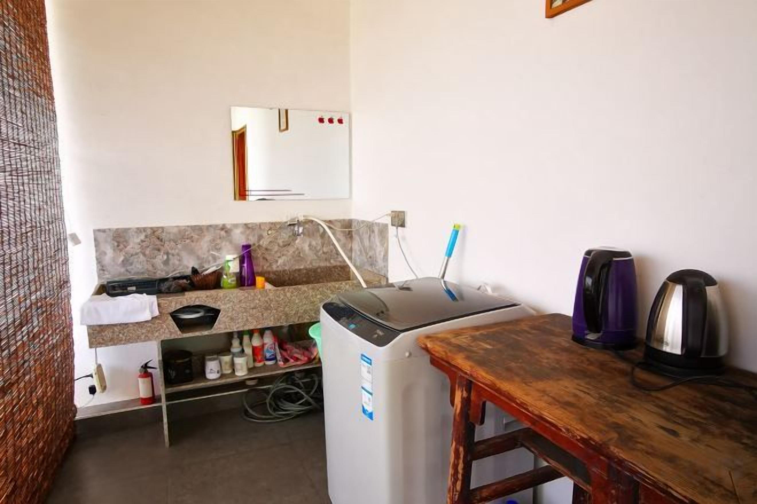 Eine kleine Küchenzeile mit Kühlschrank, Spüle und Holztisch.