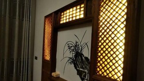 A framed artwork with a lattice design on the window, a wooden shelf, and a curtain. - Jingxutang Hostel (Wuyuan)