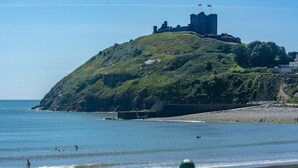 Eine Küstenansicht mit einem Schloss auf einem Hügel, Strand und Meer.
