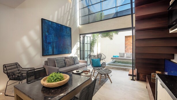 A modern living room with a sofa, a dining table, and a large abstract painting.