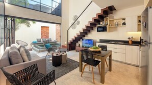 A modern living space with a dining area, kitchen, and a staircase leading to an upper level.
