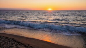A beach with waves at sunset.