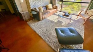 Una sala de estar moderna con sofá, una mesa de centro y un amplio ventanal con vistas al exterior.