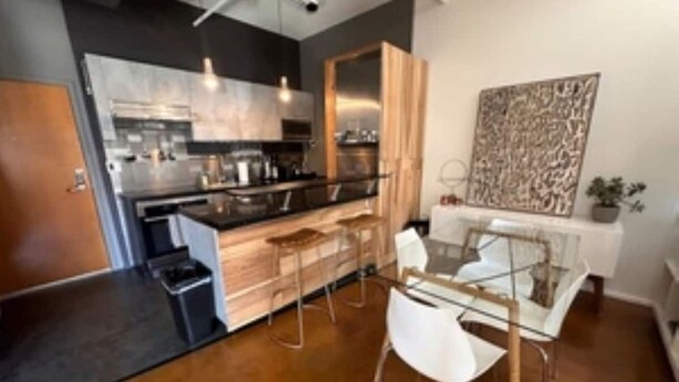 Una cocina moderna con una isla central, taburetes de bar y una mesa de comedor con sillas.