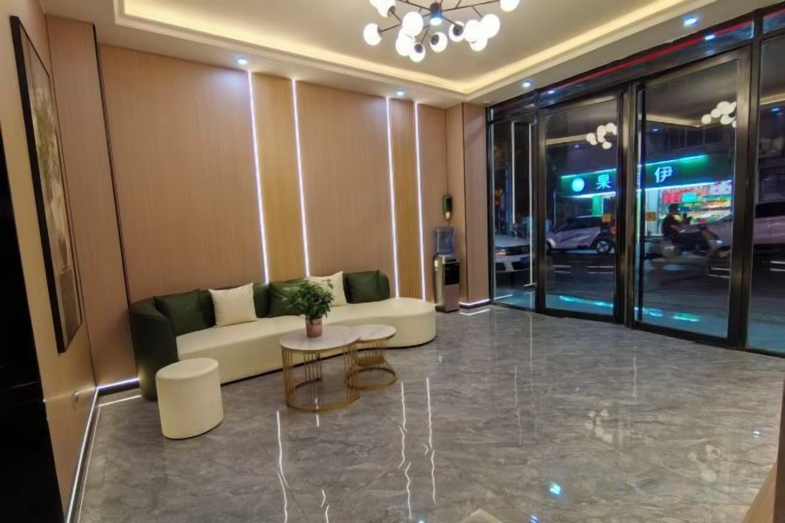 A hotel lobby with a curved sofa, a small round table, and a large window with a view of the street.