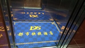 Alfombra azul con letras doradas y un logotipo, que indica un interior de hotel.