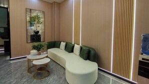 Una sala de estar moderna con un sofá curvo, una mesita redonda y una planta en maceta.