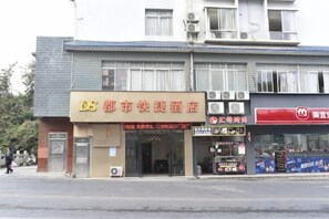 A hotel with a signboard, a storefront with a red sign, and a pedestrian crossing the street. - Guilin City Express Hotel (Guilin)