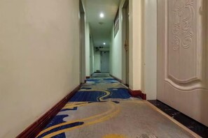 A corridor with a patterned carpet, a door with an ornate design, and a light fixture on the ceiling. - Guilin City Express Hotel (Guilin)