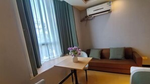 Una habitación con una mesa de comedor, un sofá, una silla y una pequeña mesa con un jarrón de flores.