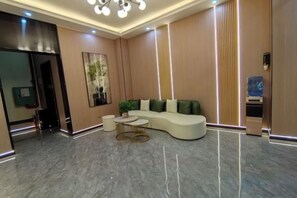A modern lobby with a curved sofa, a small round table, and a reception desk. - Guilin City Express Hotel (Guilin)