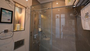 Um chuveiro com paredes de vidro, um corrimão, um porta-toalhas com uma toalha e uma placa emoldurada na parede.