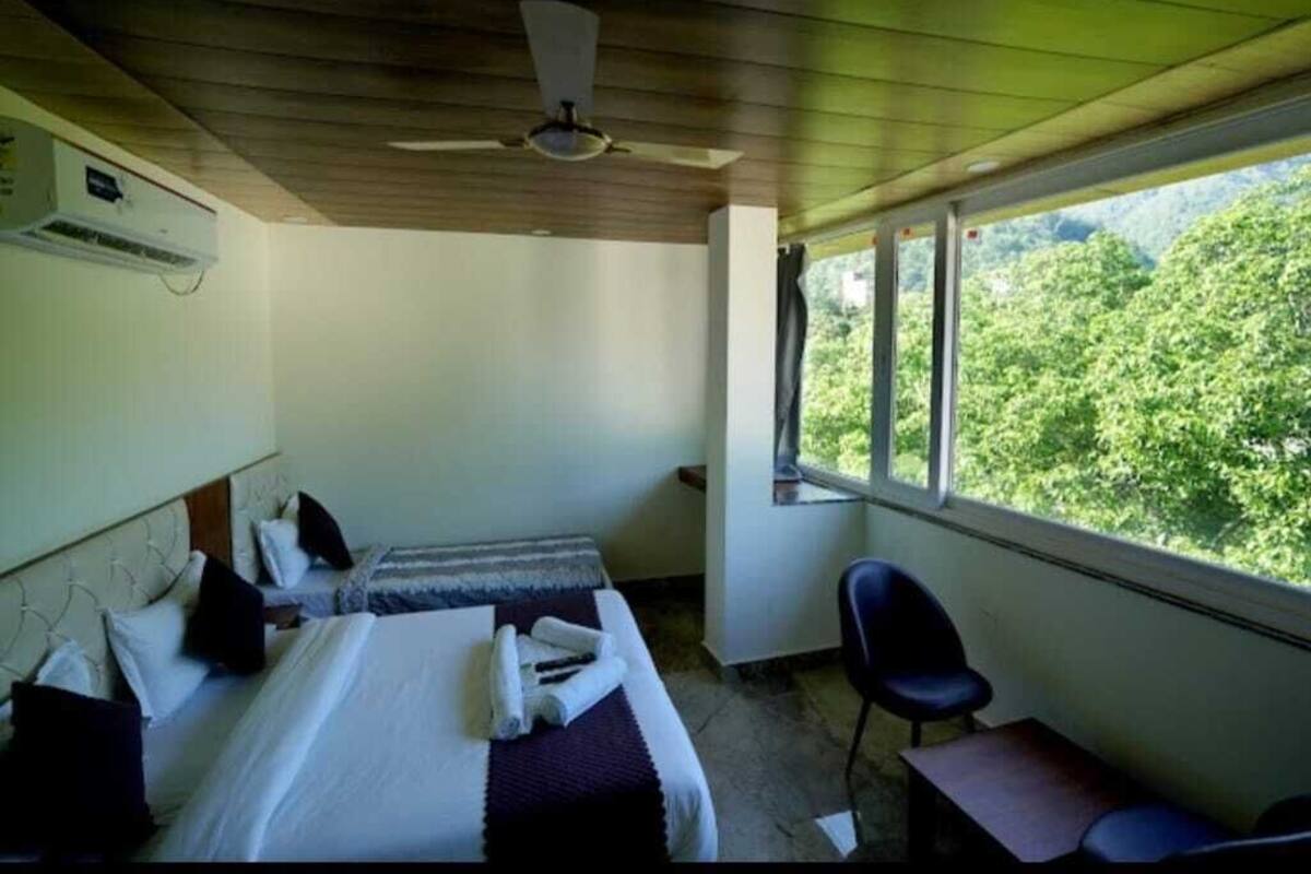 A room with a bed, a chair, and a window overlooking greenery.