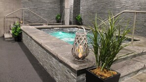 Un espace de détente avec un mur en pierre, un jacuzzi et une lanterne.
