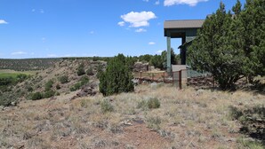 A modern building with a flat roof and a large window, surrounded by a fenced area and trees. - New Listing!! Luxury cliff-side retreat. Isolated & Serene with EPIC views. (Show Low)