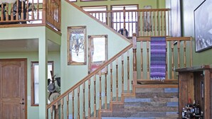 A spacious living area with a wooden staircase, a leather couch, a fireplace, and a view of the upper floor. - New Listing!! Luxury cliff-side retreat. Isolated & Serene with EPIC views. (Show Low)