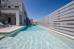 A modern hotel with a swimming pool, a covered outdoor seating area, and a view of the city.