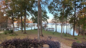 Une terrasse en bois avec une table et des chaises, donnant sur un lac où se trouvent des quais et un kiosque.