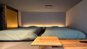 Une petite chambre moderne avec deux lits simples, une table de chevet en bois et une petite table.