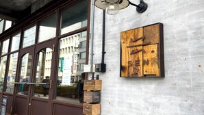 Une façade d’immeuble avec une enseigne en bois indiquant la présence de chambres d’hôtes, d’un salon d’accueil et d’un bar appelé Karly.