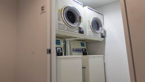 Une buanderie équipée de deux machines à laver superposées et d’un panneau de commande.