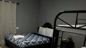 A bedroom with a single bed, a bunk bed, a nightstand, and a small table. - Rancho Agua Fría (Jucuarán)