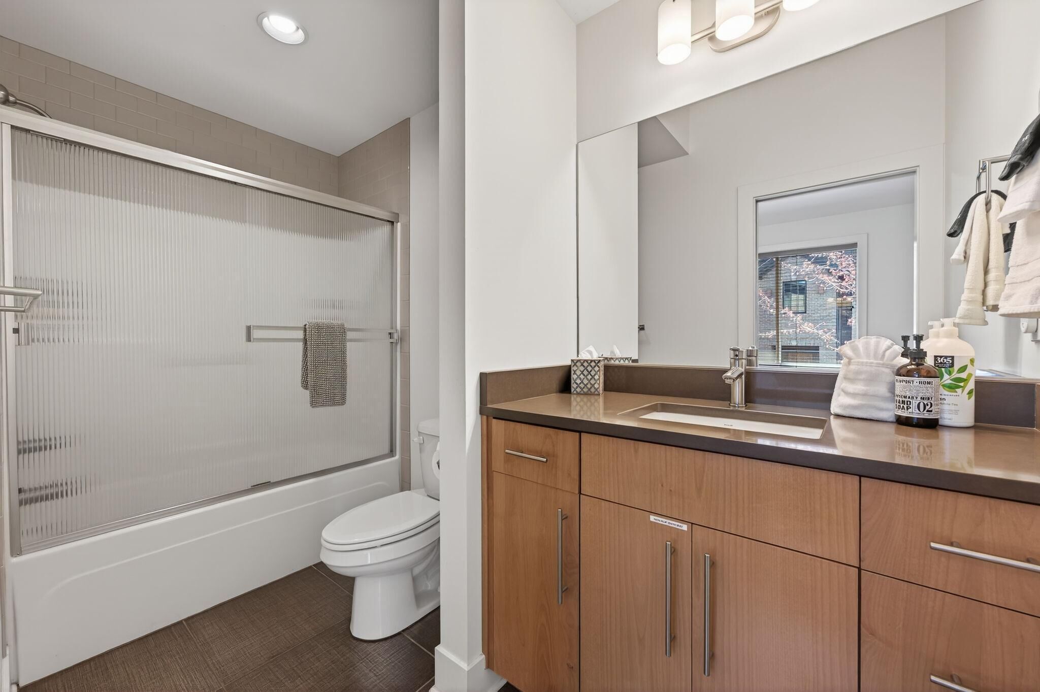 Une salle de bain moderne avec une douche à parois de verre, des toilettes et des meubles en bois.