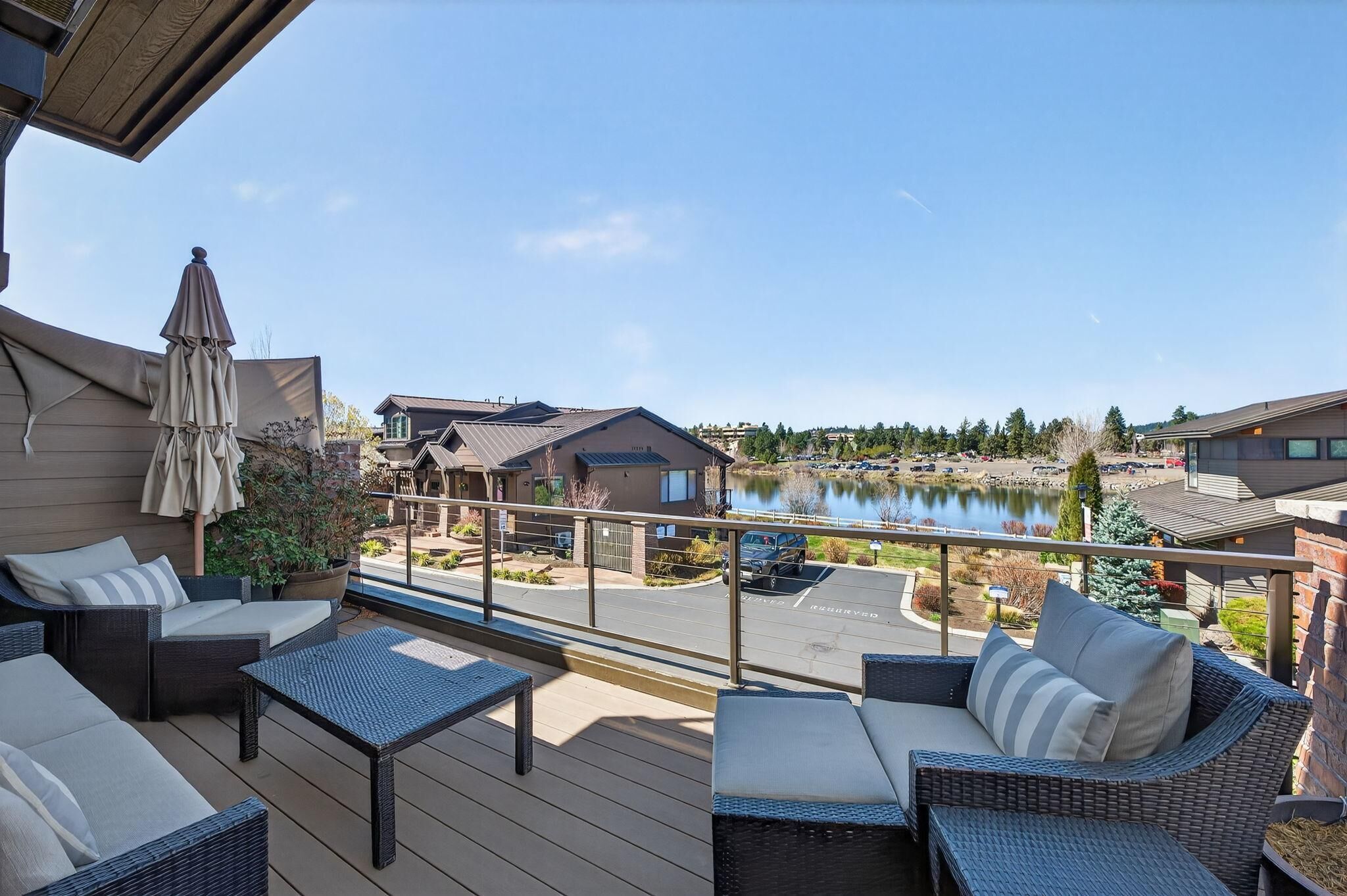 A balcony with wicker furniture, a view of a lake, and a parking area.