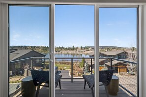 A balcony with a view of a lake, houses, and a clear sky.