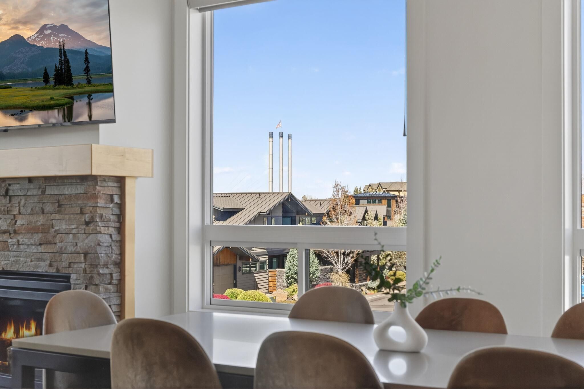 A dining area with a stone fireplace, a large window with a view of buildings and a mountain.