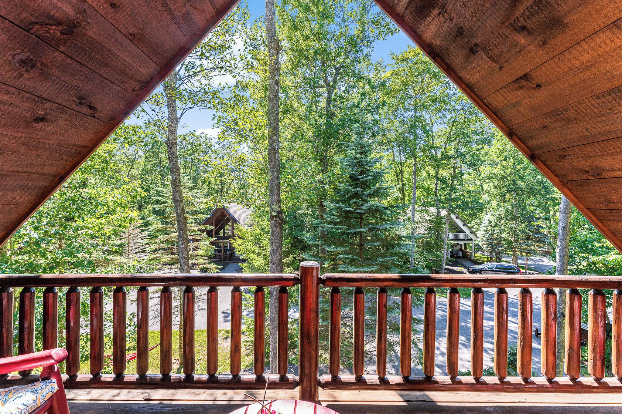 A wooden deck with a view of a forest and a cabin.