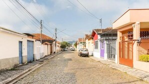 Una calle adoquinada flanqueada por casas coloridas, algunas con rejas y otras con persianas cerradas.