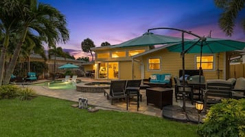 A residential property with a swimming pool, outdoor seating, and a patio area.