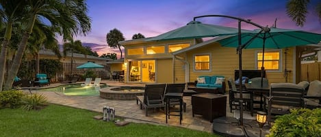 A residential property with a swimming pool, outdoor seating, and a patio area.