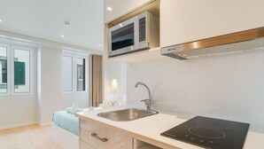 Una cocina moderna con microondas integrado, pileta de acero inoxidable y cocina por inducción negra.