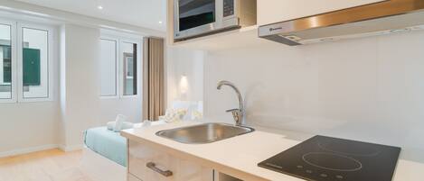 A modern kitchen with a built-in microwave, stainless steel sink, and a black induction cooktop.