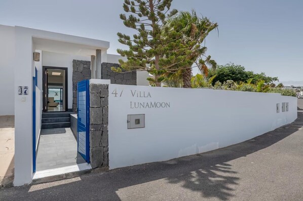 A modern villa entrance with a stone wall, a blue door, and a sign reading "Villa Lunamoon." - Villa LunaMoon (Playa Blanca)