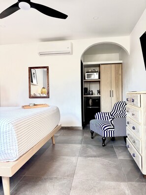 Een slaapkamer met een bed, een stoel, een kledingkast en een plafondventilator.