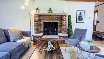 A living room with a brick fireplace, a sofa, a chair, and a coffee table.