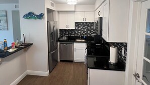 A compact kitchen with white cabinets, a black countertop, and a wooden ceiling. - Coastal 3 Bedroom, heated pool, walk to the beach and restaurants (Cocoa Beach)