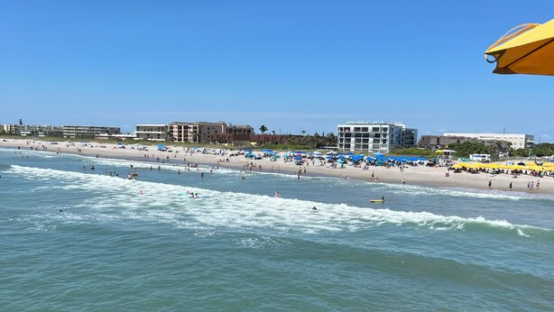 A beach with umbrellas and people. - Coastal 3 Bedroom, heated pool, walk to the beach and restaurants (Cocoa Beach)