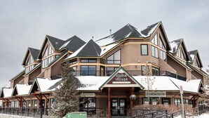 Et flere-etagers hotel med et skiløbsresorts skilt, store vinduer og et tag dækket af sne.