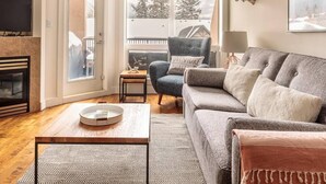 En hyggelig stue med pejs, sofa, sofabord og tv.